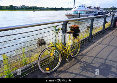 Gelbes Fahrrad mit Restaurantwerbung „Kasematten“ an der Rheinpromenade in Düsseldorf. Stockfoto