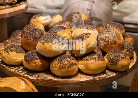 Frische Brötchen mit Mohnsamen auf einem Holzblech. Bäckerei in der türkei, Kleinbetrieb, Brotbacken. Stockfoto