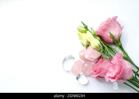 Schöne rosa eustoma (lisianthus) blüht in voller Blüte mit Rosenquarz und Bergkristall. Blumenstrauß auf weißem Hintergrund Stockfoto