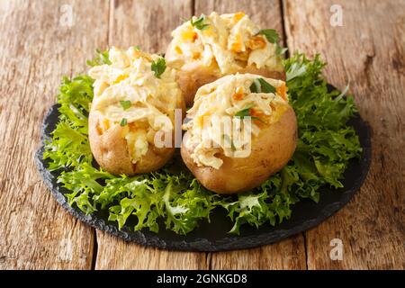 Englisches Essen gebackene Kartoffeln mit Krönungshuhnsalat mit Gewürzen und getrockneten Aprikosen in der Nähe auf einem Schieferbrett auf dem Tisch. Horizontal Stockfoto