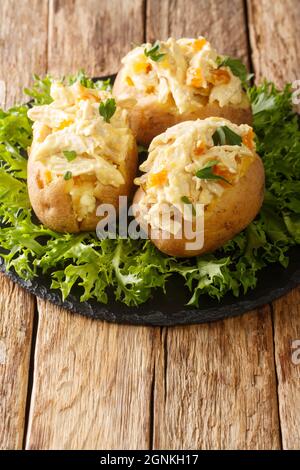 Gebackene Kartoffeln gefüllt mit Krönungshuhnsalat aus nächster Nähe auf einem Schieferbrett auf dem Tisch. Vertikal Stockfoto