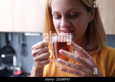 Junge Frau trinkt Tee aus durchsichtiger Tasse aus der Nähe Stockfoto