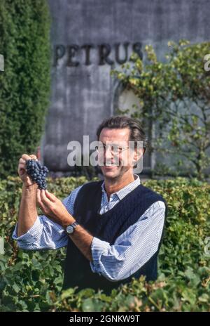 CHATEAU PETRUS Christian Moueix lächelt und hält während der Lese im Weinberg von Château Pétros, Pomerol, Gironde, Frankreich, ein paar merlot-Trauben. ... Stockfoto