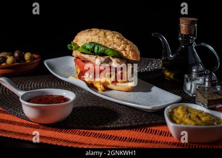 Filet-Sandwich mit Tomaten, Salat, Ketchup-Sauce und Senf. Stockfoto