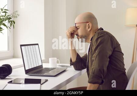 Gestresste müde Mann hat Augenbelastung wegen der ständigen Arbeit an seinem Laptop-Computer Stockfoto