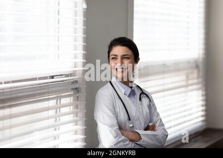 Selbstbewusste indische Ärztin, die am Fenster steht Stockfoto