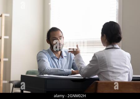 Junger männlicher Patient besucht Arzt und konsultiert junge Hausärztin Stockfoto