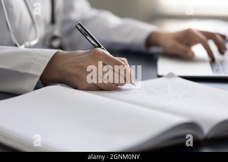 Ärztin für Hausärzte, die Krankenakten im Arbeitsbuch schreibt Stockfoto
