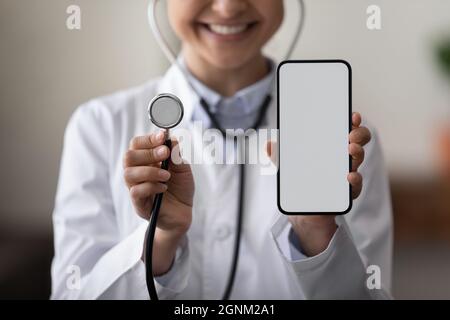 Glückliche Ärztin mit Stethoskop und leerem Smartphone-Bildschirm Stockfoto
