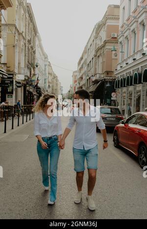 Eine vertikale Aufnahme eines romantischen Paares in passenden Outfits, das in einer Stadt unterwegs ist Stockfoto