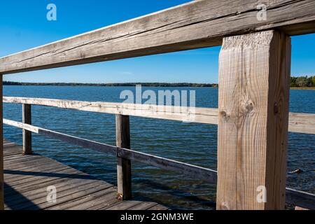 Helsinki / Finnland - 26. SEPTEMBER 2021: Nahaufnahme eines Holzgeländers einer alten Seebrücke. Blaues Meer im Hintergrund. Stockfoto