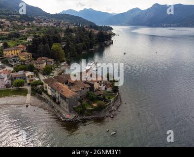 Kleines Dorf auf einer Halbinsel des Comer Sees neben einem Yachthafen mit festfahrenden Booten - Aerial View, Lierna, Lombardei, Italien Stockfoto