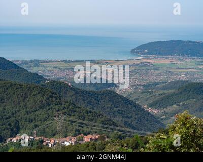 Blick auf die Marmorsteinbrüche von Carrara, die in die Seite des Berges eingeschnitzten Wege und die Stadt Carrara und die Küste davor. Stockfoto