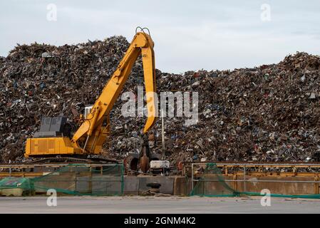 Southampton, England, Großbritannien. 2021. Eine gelbe Raupenbaggermaschine an einem Kai, die Metall bewegt, bevor sie zum Export auf ein Frachtschiff geladen wird. Stockfoto