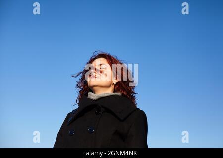 Schöne Rothaarige Frauen im Winter auf dem Dach auf dem blauen Himmel Hintergrund. Außenfoto. Stockfoto