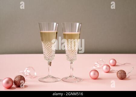 Zwei Gläser Wein mit weihnachtlichen Ornamenten auf rosa Hintergrund Stockfoto
