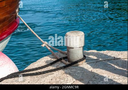 Poller und Festmacherseile. Festmacherbollard mit schweren Festmacherseilen. Nahaufnahme eines Pollers mit Seil in der Marina Stockfoto