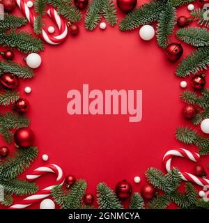 Rahmen aus Weihnachtsschmuck Tannenzweigen auf rotem Hintergrund. Leer mit einem Kopierbereich für Text Stockfoto