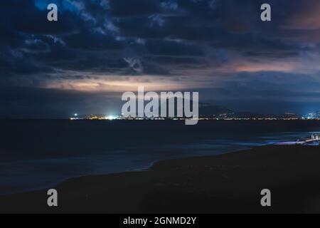 Die Küste von Denia mit ihren dramatischen Wolken glänzte vom Mondlicht aus gesehen vom Strand von Daimus, Spanien Stockfoto