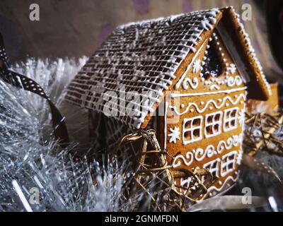 Lebkuchenhaus mit weißer Glasur in Neujahr und Weihnachten Muster in weißem Schnee Lametta dekoriert Stockfoto