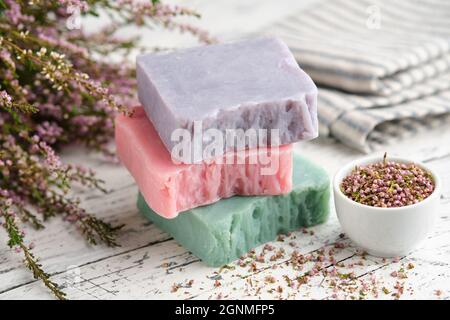 Hausgemachte Naturseifen und Heideblumen auf weißem Tisch. Stück Bio-Seife. Stockfoto