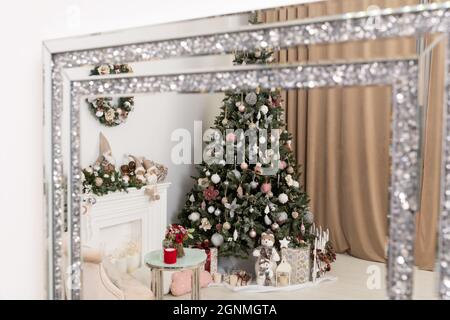 Spiegelung im Spiegel des weihnachtsbaums. Hoher Weihnachtsbaum in Blau dekoriert. Unter dem Baum befinden sich große Schachteln mit Geschenken. Stockfoto