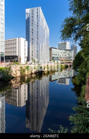 Der Apartmentblock Riverside und das Lowry Hotel spiegeln sich im Fluss Irwell, Salford, Manchester, Großbritannien, wider Stockfoto