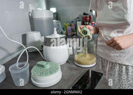 Nahaufnahme des elektrischen Mixers in der Hand einer unbekannten Frau, die ihn auf der Küchentheke hält, die Kartoffelbrei zubereitet Stockfoto