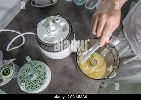 Nahaufnahme des elektrischen Mixers in der Hand einer unbekannten Frau, die ihn auf der Küchentheke hält, die Kartoffelbrei zubereitet Stockfoto