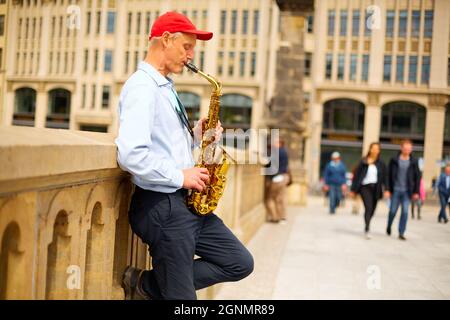 Ein Straßenmusiker spielt auf einer Stadtstraße das Saxophon. Berlin, Deutschland - 05.17.2019 Stockfoto