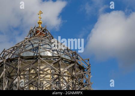 Graue Holzgerüste auf einer Kuppel der russischen christlichen Kirche bei Tageslicht am blauen Himmel mit weißen Wolken Stockfoto