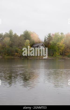 Ein gemütliches Haus am See in der herbstlichen Landschaft Stockfoto
