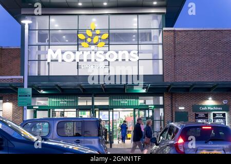 Abendkäufer vor dem Eingang zu Morrisons, die auf dem Parkplatz, Sidcup Kent, England, auf ihr Auto zulaufen Stockfoto