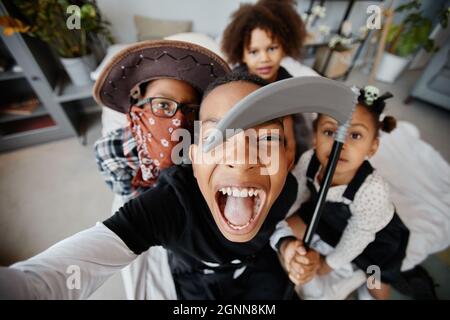 POV-Aufnahme von aufgeregten afroamerikanischen Kindern, die an Halloween Selfie machen, während sie Kostüme tragen Stockfoto