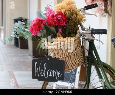 Ein Korbkorb mit Herbstblumen und ein Willkommensschild begrüßen die Käufer in einem Geschäft in Monterey, CA. Stockfoto