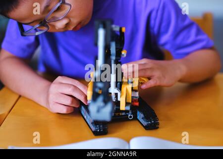 Kind Junge Baumechaniker Lego Backstein Blöcke Technik auf dem Tisch zu Hause während der Sommerpause gesetzt. Kinderwissenschaft, Innovation, Technik und Kreativität. Stockfoto