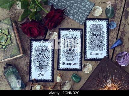 Wahrsageritual mit Tarot-Karten, Rosen und Kristallen auf dem Hexentisch. Esoterischer, gotischer und okkulter Hintergrund, mystisches Halloween-Konzept. Stockfoto