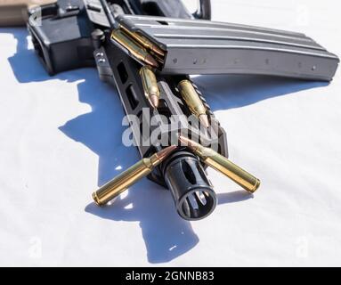 Ein Gewehrmagazin mit 223 Kalibern auf einem kurzen AR15-Gewehr mit Barreled und zusätzlichen Kugeln daneben auf weißem Hintergrund Stockfoto