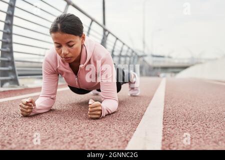 Junge schöne Frau, die in der Bar steht, während sie im Freien im Stadion trainiert Stockfoto