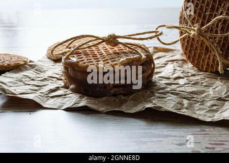 Low-Key-Fotografie. Nahaufnahme eines Stapels Stroopwafels mit Sisalbogen, neben anderen Keksen. Stockfoto