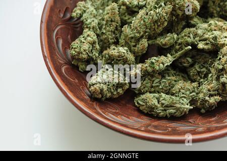 Cannabisknospen in brauner Tonschale, flacher Lat, Draufsicht. Marihuana-Blüten aus nächster Nähe. Hanf Erholung, Canna Küche, Legalisierungskonzept. Stockfoto