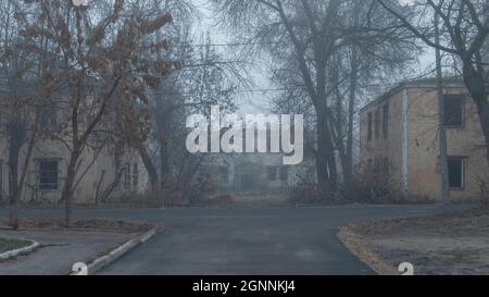 Eine verlassene Straße mit verlassenen zweistöckigen Häusern an einem nebligen Tag Stockfoto