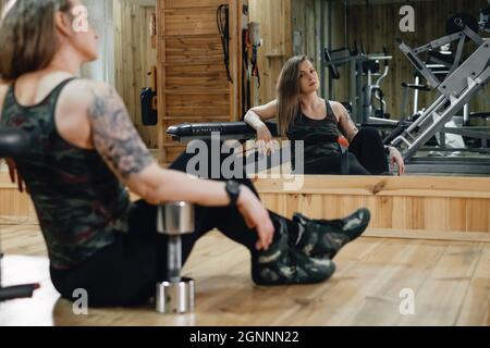 Frau, die im Fitnessstudio trainiert und Hantelpresse macht. Hubgewicht. Schöne Frau mittleren Alters Powerlifter mit Tattoo. Stark und fit Körper, gesund Stockfoto