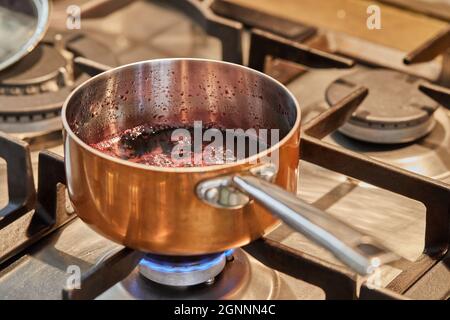 Kupferkasserolle bei niedriger Hitze auf dem Herd, um Sauce zu machen Stockfoto