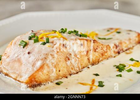 Lachsfischfilet in Bechamelsauce mit Orangenschale und grünen Zwiebeln. Französische Küche Gourmet-Essen Stockfoto