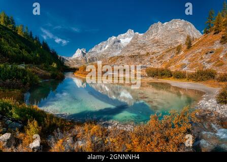 Farben der Herbstsaison ins wilde Vinschgau mit See im Vordergrund, Aostatal, Italien Stockfoto