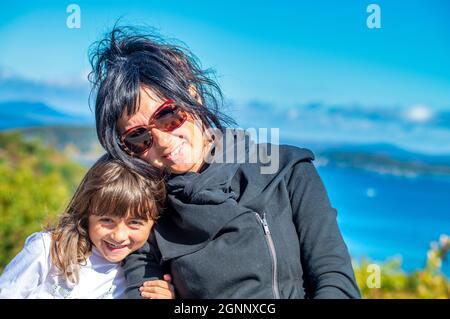 Glückliche Frau mit ihrer Tochter, die sich in der Herbstsaison in der Laublandschaft entspannt Stockfoto