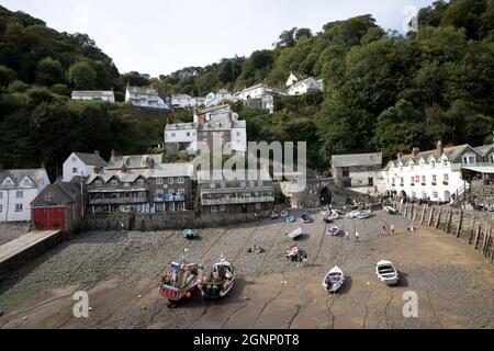 Abwechslungsreiche Häuser und Hütten im alten Dorf Clovelly, die bei Ebbe vom Hafen aus mit befahrenen Booten North Devon betrachtet werden Stockfoto