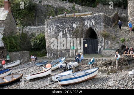 Besucher sitzen am ehemaligen Kalkofen und Torbogen mit geschwungenen Schutthüsten am Vorgewende mit kleinen Booten, die bei Ebbe Clovelly North Devon befahren wurden Stockfoto