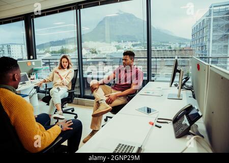 Verschiedene Designer diskutieren Logo-Designs für neue Projekte, die im offenen Büro sitzen Stockfoto